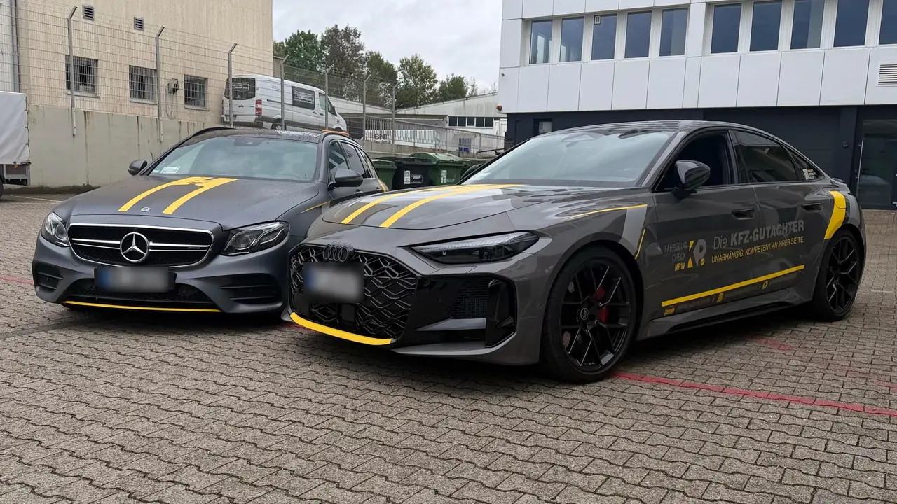 Zwei Gutachterfahrzeuge von Fahrzeugcheck.NRW in Grau mit gelben Streifen, eines mit der Aufschrift „Die Kfz-Gutachter“