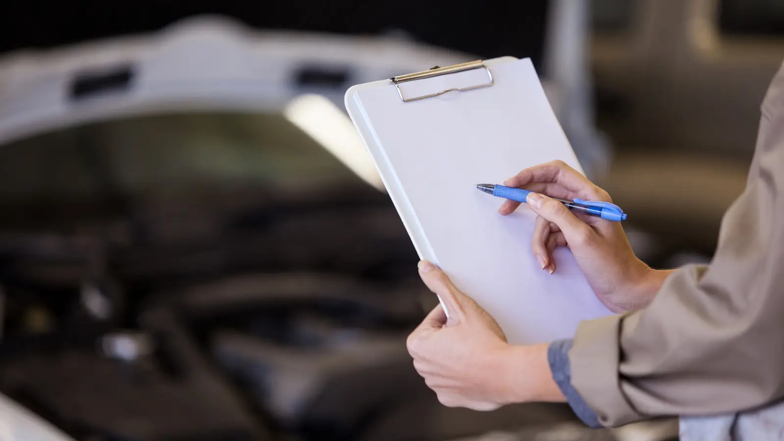Checkliste auf einem Klemmbrett vor einer geöffneten Motorhaube