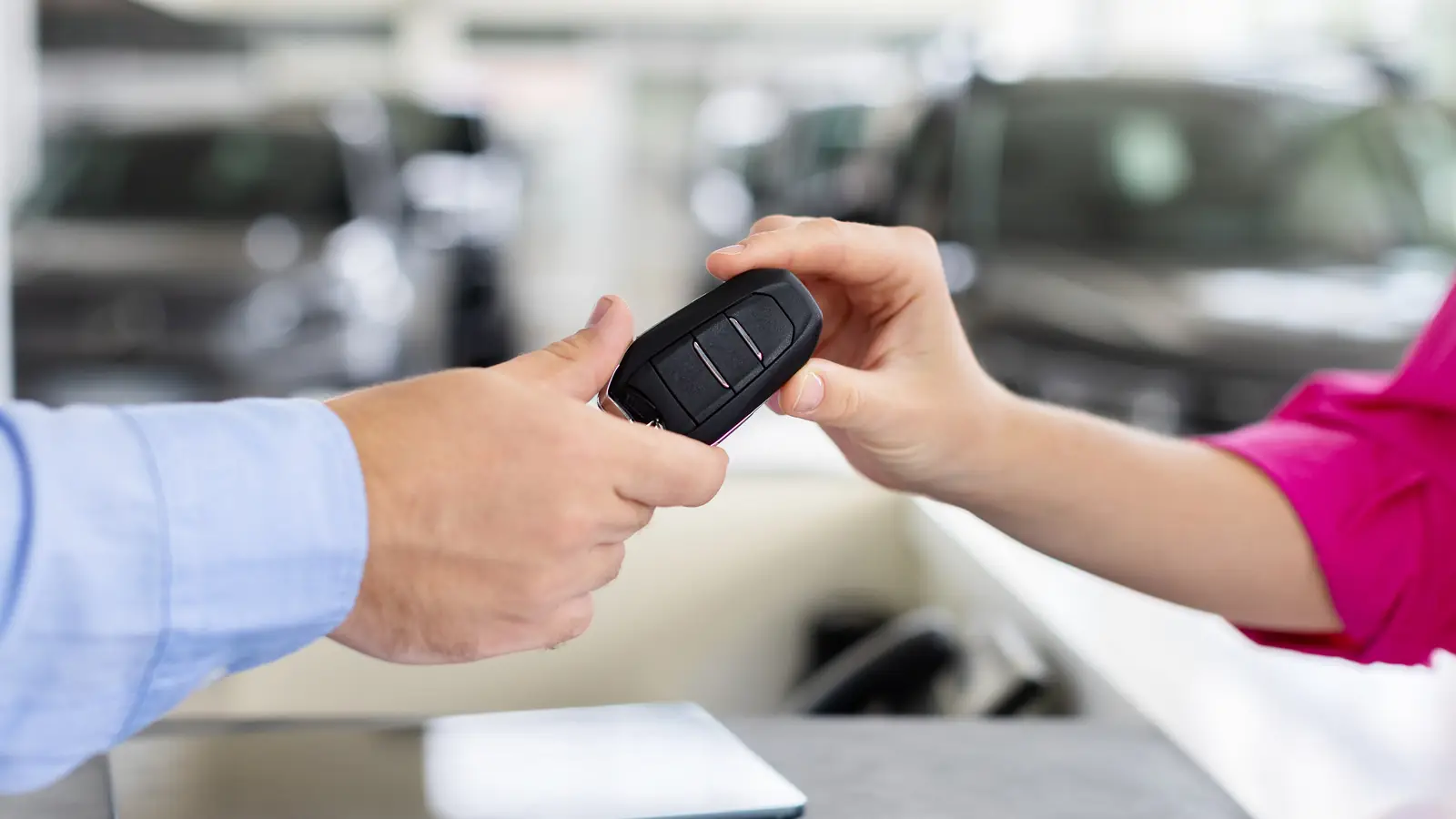 Übergabe eines Autoschlüssels über einen Tresen